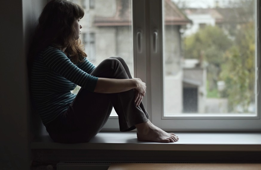 Frau sitzt in Fenster, Quarantäne