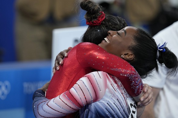 Simone Biles, of the United States, embraces teammates Sunisa Lee after dismounting from the balance beam during the artistic gymnastics women&#039;s apparatus final at the 2020 Summer Olympics, Tuesd ...