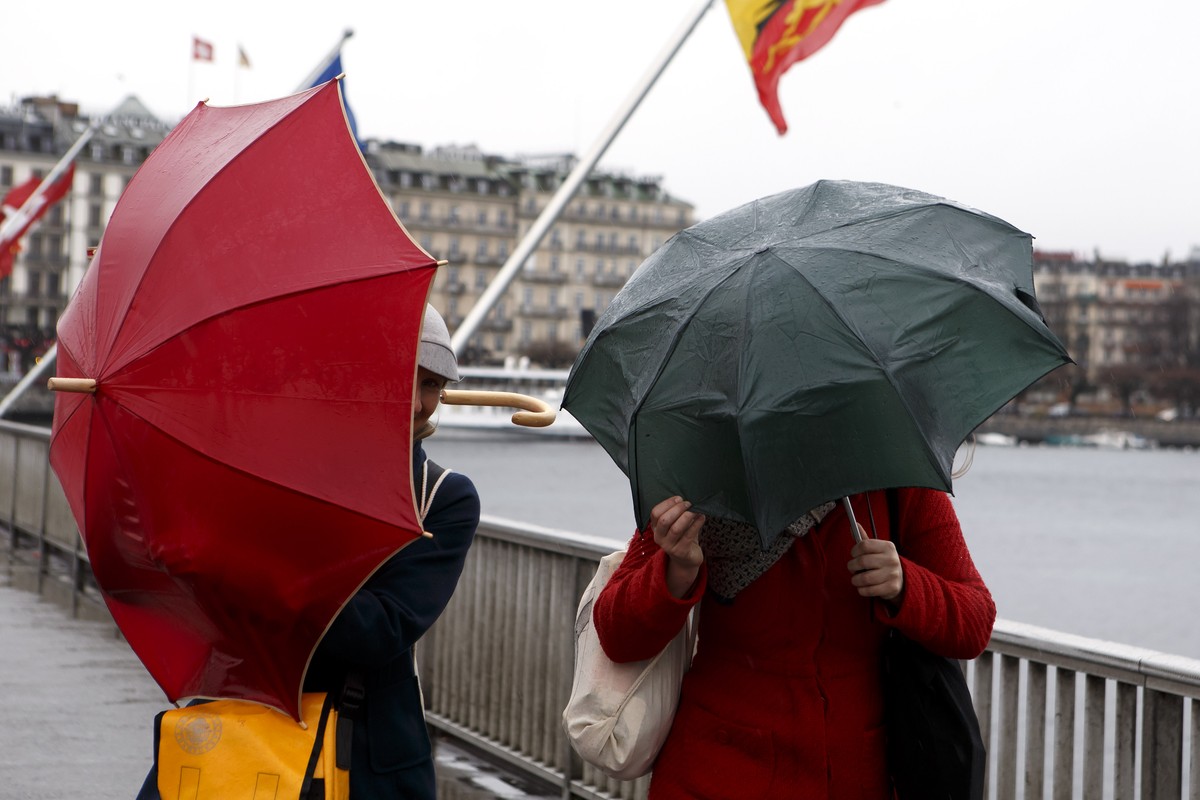 Pedestrians protect themselves with their umbrellas from the rain and of strong wind on the Mont Blanc bridge, which crosses the Lake Geneva, in Geneva, Switzerland, on Saturday, February 4, 2017. (KE ...