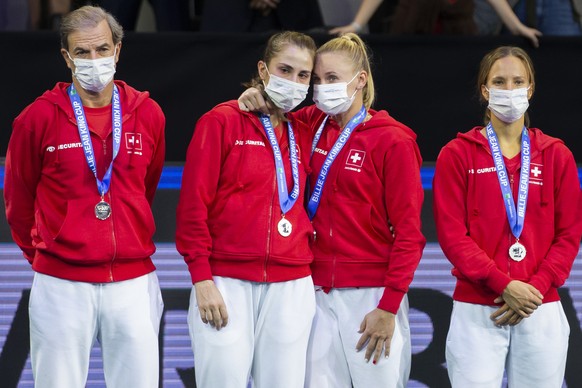 Switzerland&#039;s team captain Heinz Guenthardt, Belinda Bencic, Jil Teichmann and Viktorija Golubic, from left, react during the victory ceremony after the Billie Jean King Cup final tennis match be ...