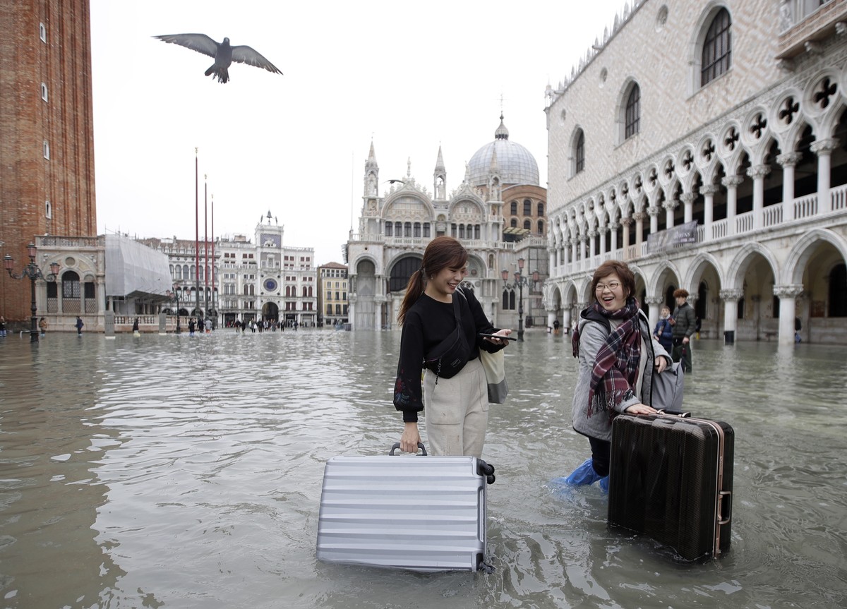 Tourists push their luggage in a flooded St. Mark's Square, in Venice, Wednesday, Nov. 13, 2019. The high-water mark hit 187 centimeters (74 inches) late Tuesday, Nov. 12, 2019, meaning more than ...