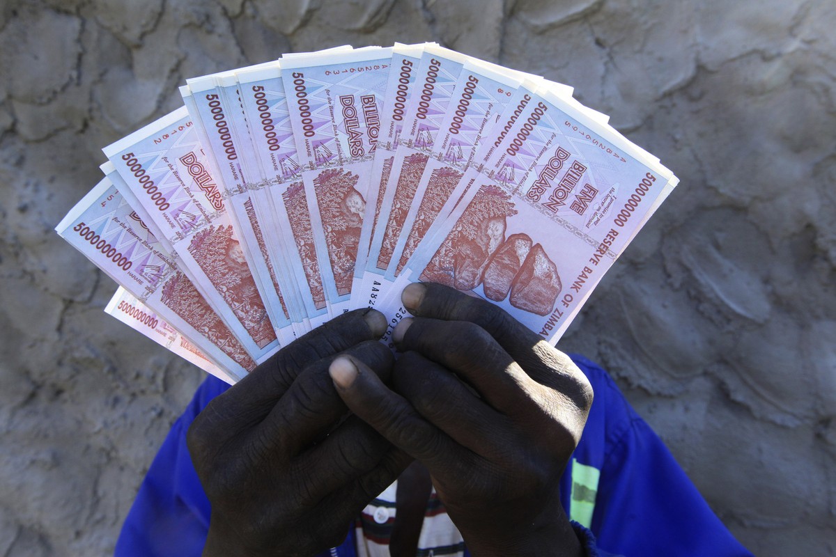 A man holds a handful of 5 Billion Zimbabwean dollar notes, in Harare, Friday, June, 12, 2015. Zimbabwe's central bank says banknotes from its old currency, which collapsed and was discarded year ...