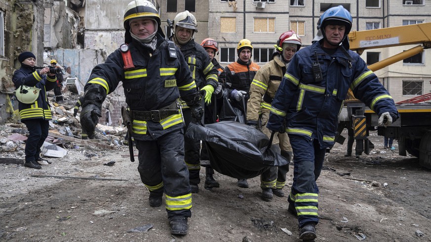 Rescue workers carry the body of a man who was killed in a Russian missile strike on an apartment building in the southeastern city of Dnipro, Ukraine, Monday, Jan. 16, 2023. (AP Photo/Evgeniy Malolet ...