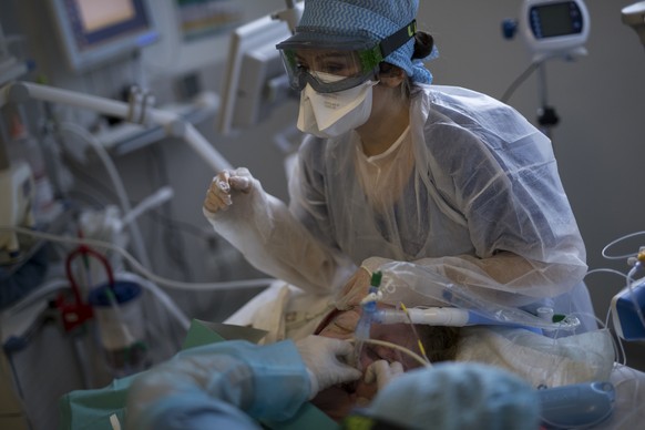 Nurses clean and adjust an endotracheal tube providing respiratory assistance to a 61-year-old COVID-19 patient at the ICU in the La Timone hospital in Marseille, southern France, Thursday, Nov. 12, 2 ...