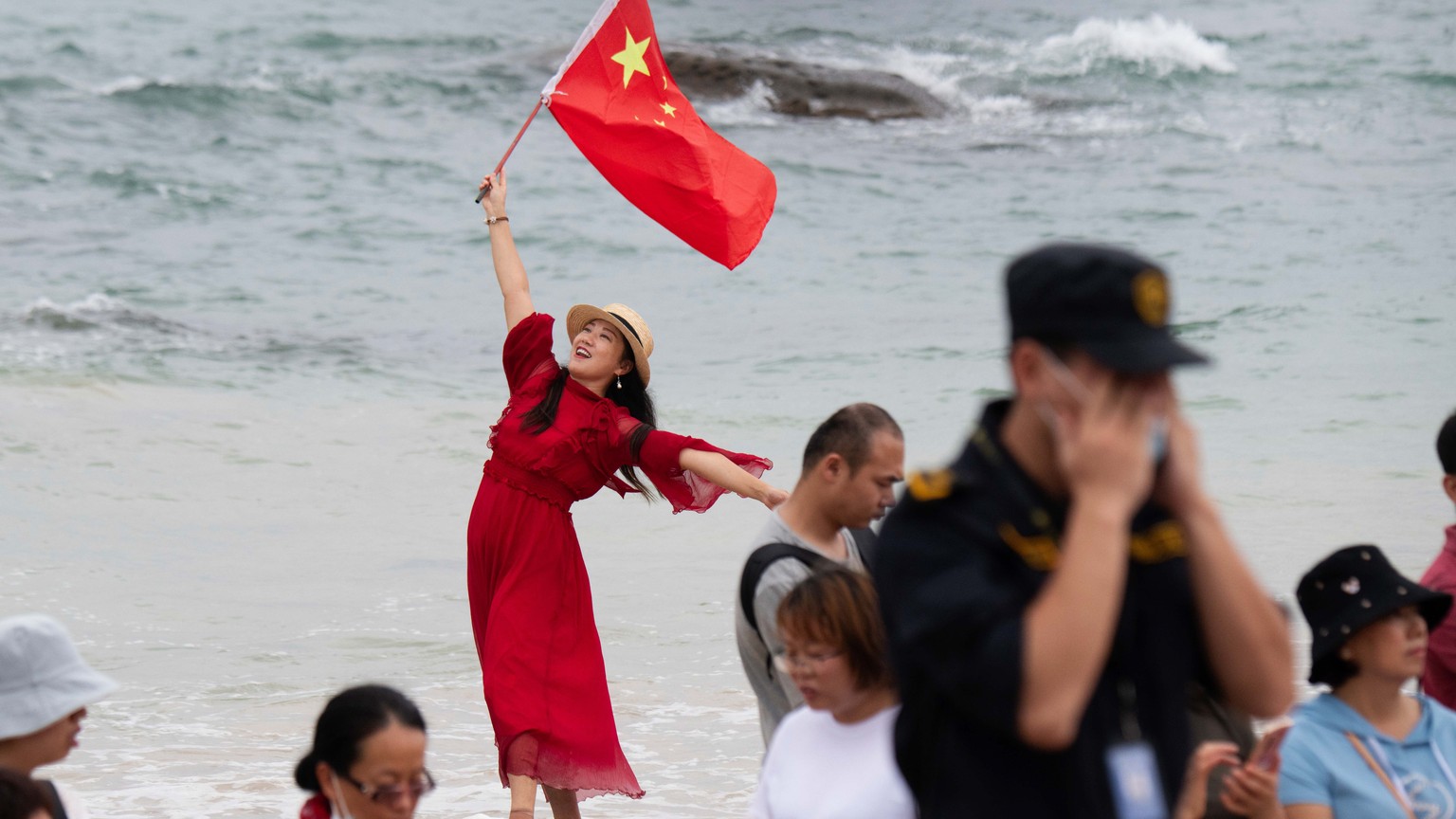 epaselect epa09166965 A woman holds up the Chinese national flag as people gather to watch the the launch of the Long March 5B rocket carrying China&#039;s Tianhe space station core module from the We ...