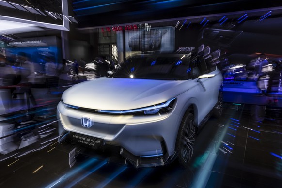epa09149054 A photo taken with a long exposure shows people looking at the Honda SUV e: car on display at the Honda trade fair stand during the first day of the Auto Shanghai 2021 motor show in Shangh ...