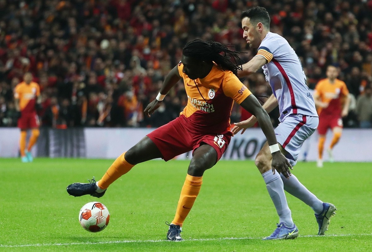 epa09831988 Bafetimbi Gomis (L) of Galatasaray in action against Sergio Busquets of FC Barcelona during the UEFA Europa League round of 16, second leg soccer match between Galatasaray SK and FC Barcel ...