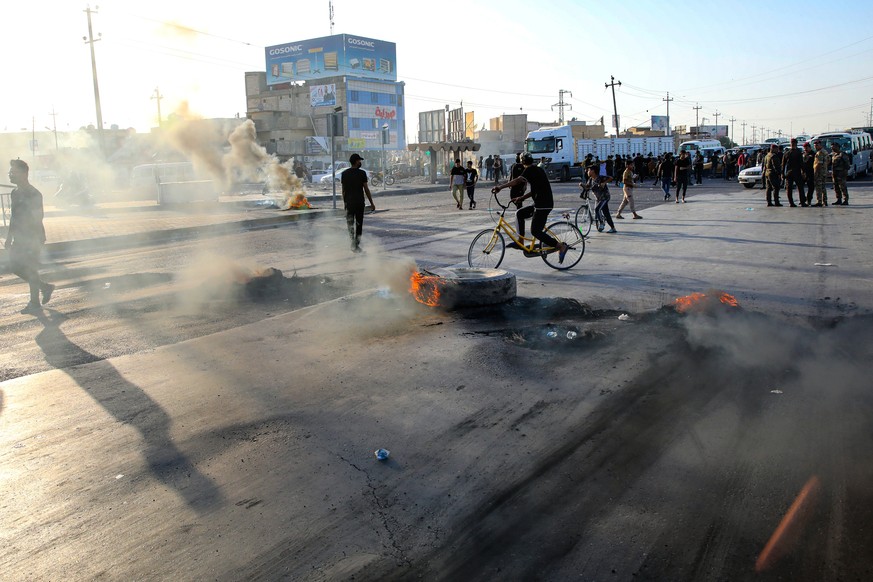 Supporters of hardline Iraqi Shiite factions block streets and burn tires after the Electoral Commission announced the results of the parliamentary elections in Basra, Iraq, Sunday, Oct. 17, 2021. Pro ...