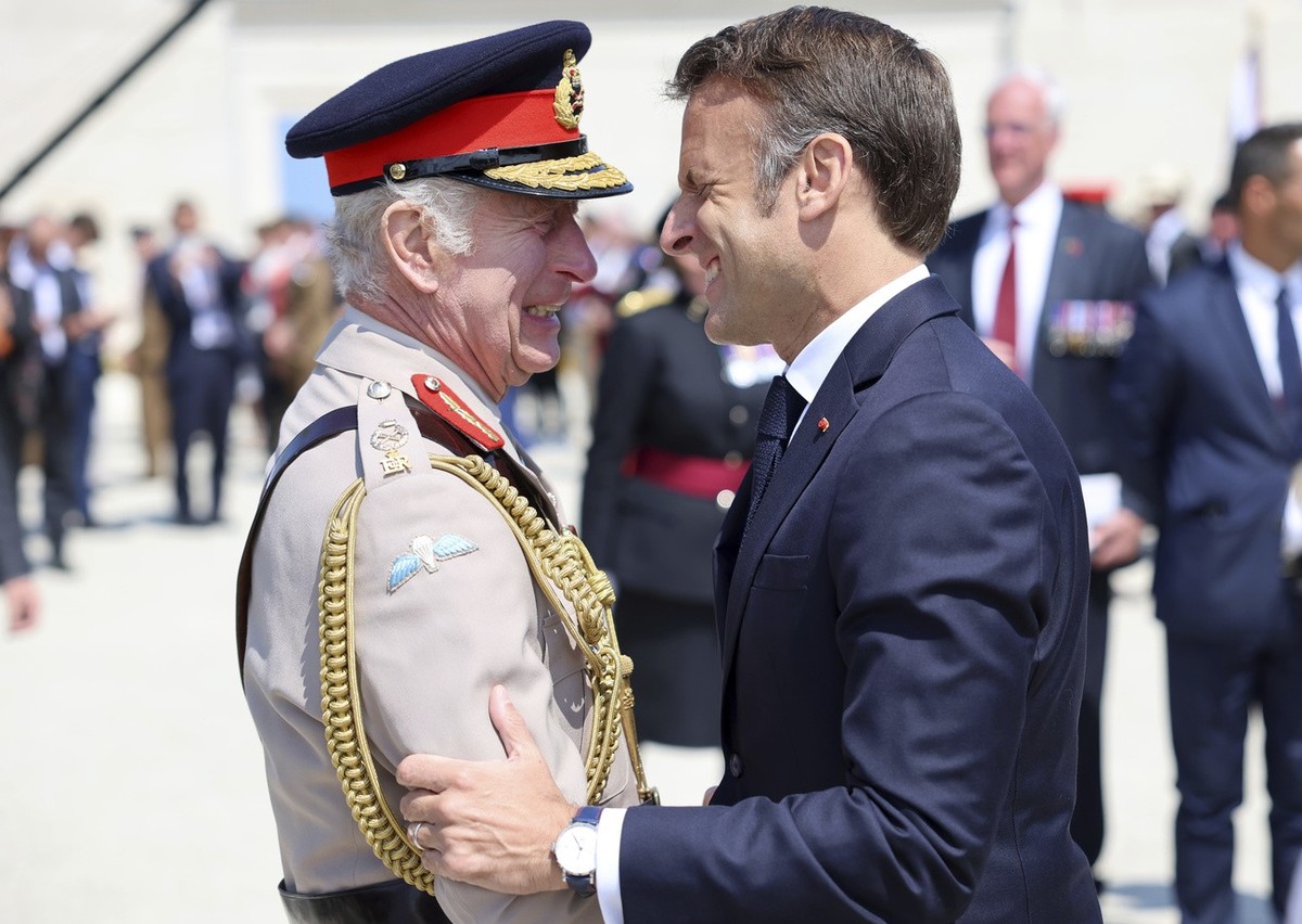 Britain's King Charles III and President of France, Emmanuel Macron, right, laugh during the UK Ministry of Defence and the Royal British Legion's commemorative event at the British Normandy ...