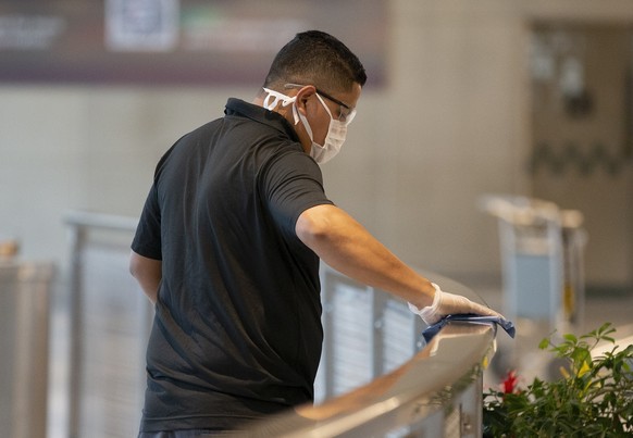 epa08290215 A cleaning crew member wipes down railings with disinfectant outside the international arrivals inside Boston&#039;s Logan International Airport, in Boston, Massachusetts, USA 12 March 202 ...