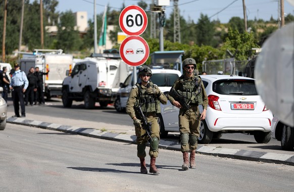 epa09173219 Israeli troops gather at the scene where a Palestinian woman was shot and wounded after allegedly trying to stab an Israeli soldier, in Gush Etzion Junction in the West Bank, 02 May 2021.  ...