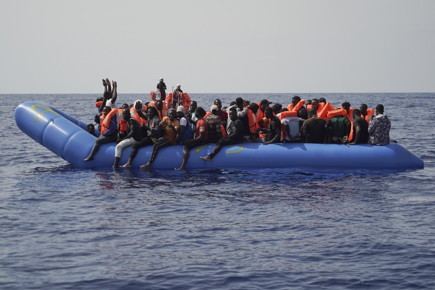 Men aboard a blue plastic boat point to the sky in the Mediterranean Sea, Tuesday, Sept. 17, 2019. The humanitarian rescue ship Ocean Viking saved 109 people from two unseaworthy boats. (AP Photo/Rena ...