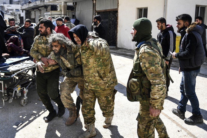 In this photo taken on Sunday, March 1, 2020, Turkey-backed opposition fighters help a fellow fighter wounded in fighting with Syrian government forces and their allies in Sarmin, south of Idlib, Syri ...