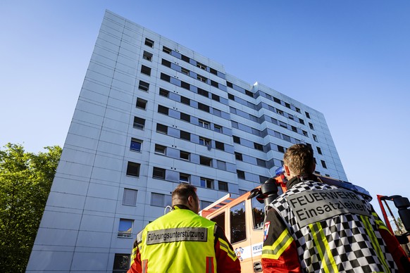 Einsatzkraefte der Feuerwehr bei einem Gebaeude nach einem Brand in einem Mehrfamilienhaus in Spreitenbach, am Montag, 8. Juli 2024. Gemaess Polizeiangaben wurden beim Brand, der im Eingangsbereich ei ...