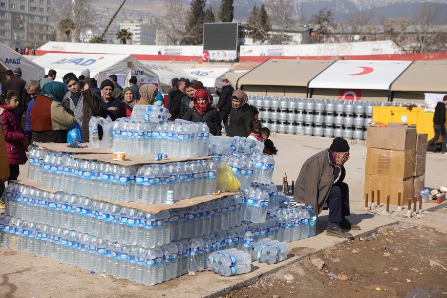 epa10460492 A man affected by the earthquake reacts at the water distribution ponit at the AFAD organization emergency shelter erected in a stadium in Kahramanmaras, Turkey, 11 February 2023. More tha ...
