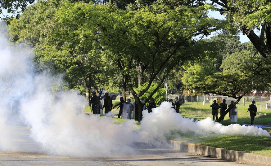 Venezuelan Bolivarian National Guard officers fire teargase towards resident that try to walks to the Military base Paramacay in Valencia, Venezuela, Sunday Aug. 6, 2017. Venezuelan ruling party chief ...