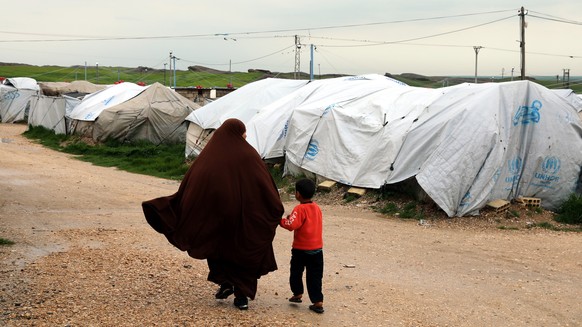 epa07473787 An unidentified woman, reportedly a wife of a suspected Islamic State (IS) fighter, walks with her son at Roj refugees camp in Hasakah, northeast of Syria, 30 March 2019. The camp which is ...