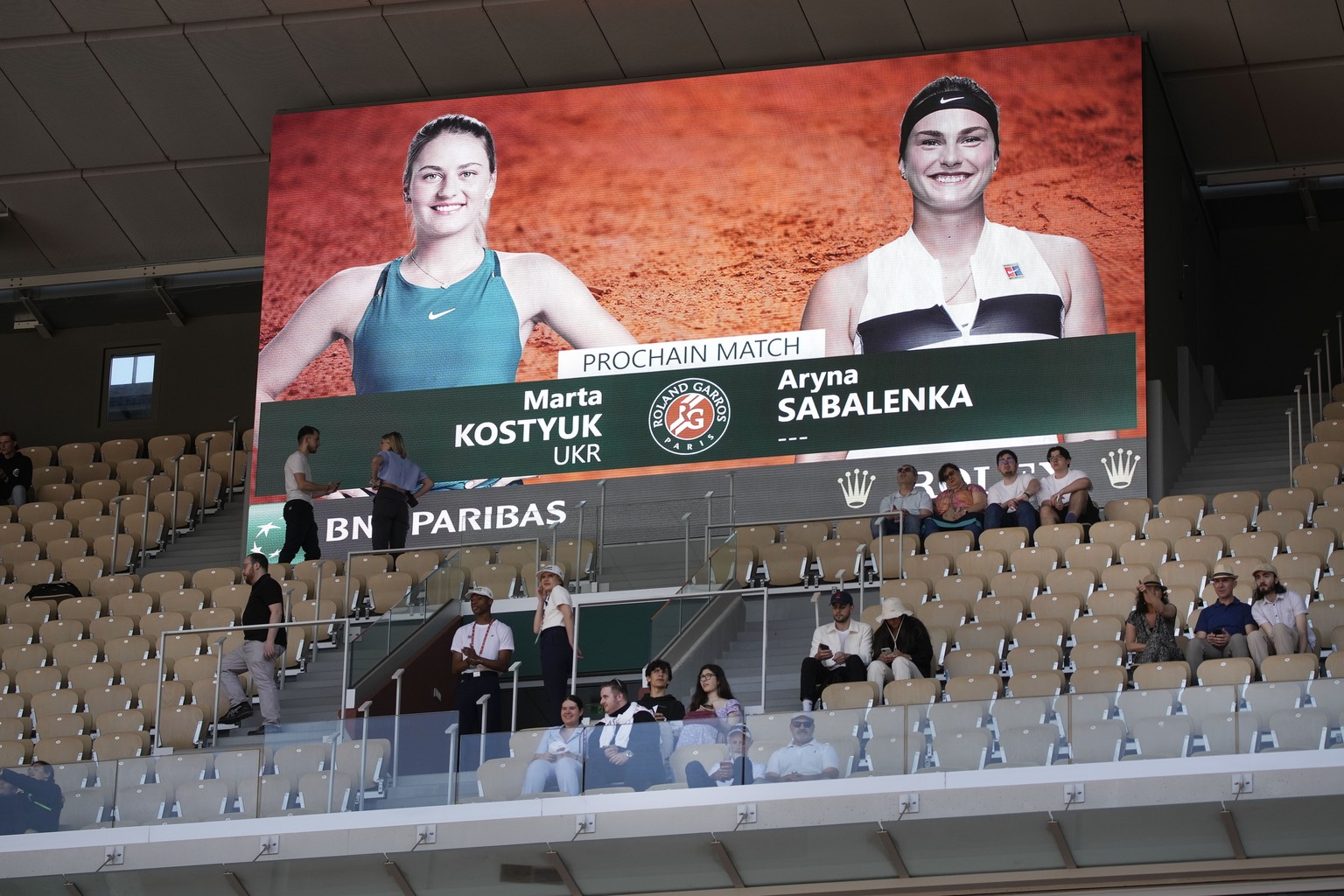 Spectators take their seats under a screen announcing the the first round match of the French Open tennis tournament between Ukraine&#039;s Marta Kostyuk and Aryna Sabalenka of Belarus at the Roland G ...