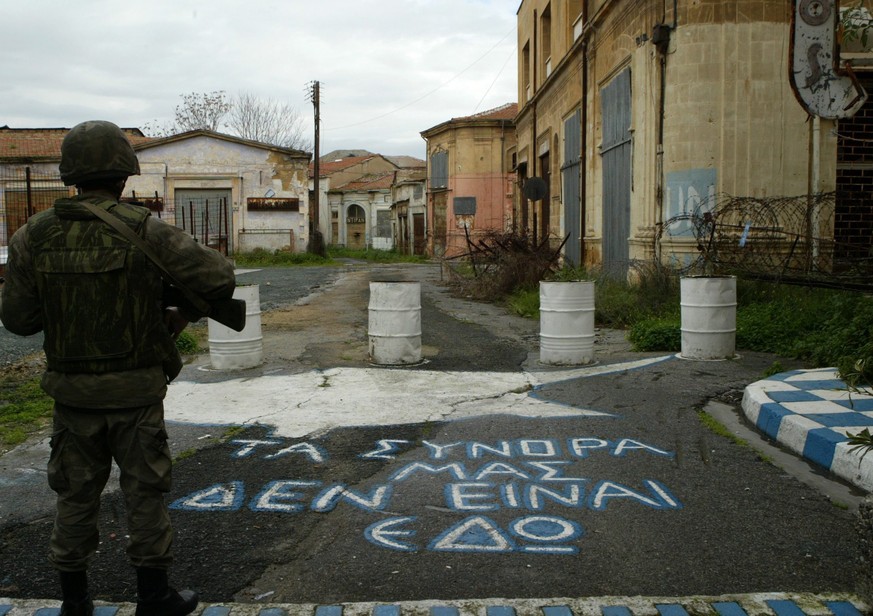 epa04321175 A Greek Cypriot sentry on duty guards his post infront of a UN buffer zone splitting the Cypriot capital Nicosia, 18 July 2014, with the words &#039;Our Border is Not Here&#039;, painted o ...