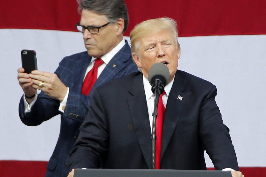 FILE - In this July 24, 2017, file photo, President Donald Trump delivers a speech to scouts as Secretary of Energy Rick Perry uses his phone at the 2017 National Boy Scout Jamboree at the Summit in G ...
