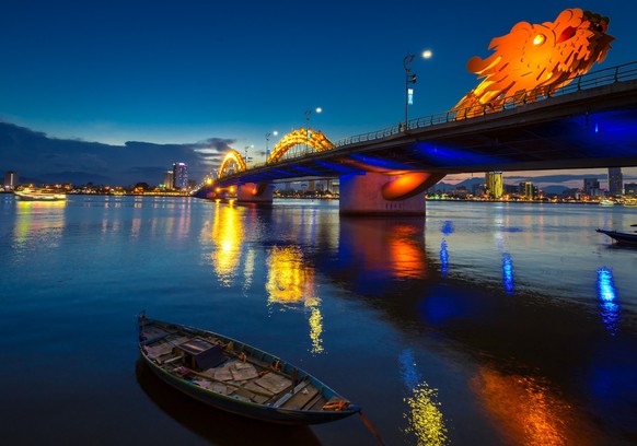Dragon Bridge in DaNang all lit up, taken in the evening just after sunset.  The bridge and city lights reflect on the great river.