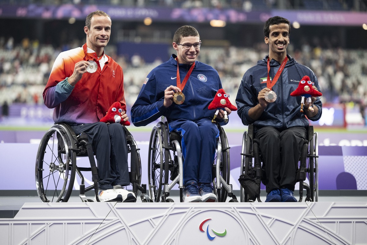 Marcel Hug of Switzerland, from left, celebrates next to Daniel Romanchuk of the United States of America and Faisal Alrajehi of Kuwait after the Men�s 5000m T54 race in the Stade de France at the 202 ...
