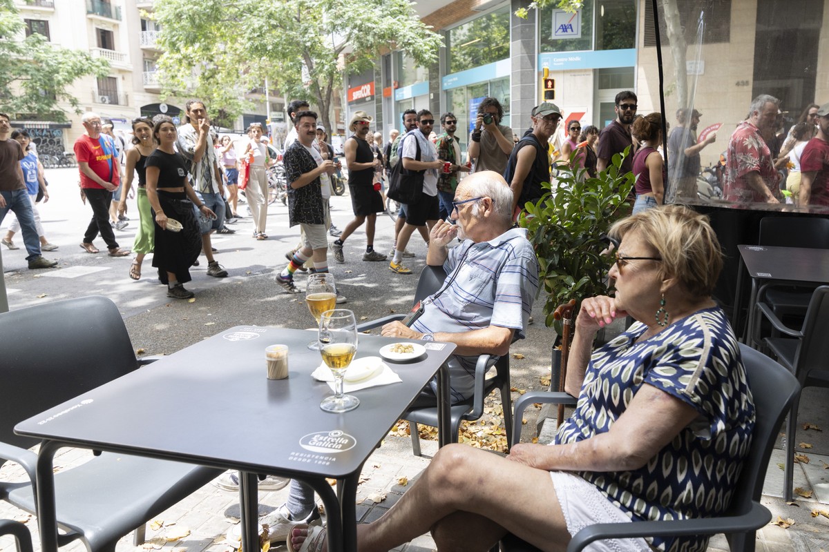 epa12178818 Tourists at the terrace of a bar look as demonstrators march to demand measures against mass tourism in their hometown, in Barcelona, Spain, 15 June 2025 (issued 16 June 2025). The protest ...