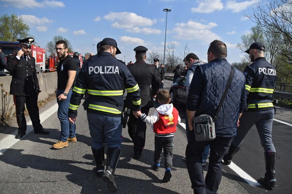epa07450606 A policeman takes a child by the hand who was on the bus set on fire by a driver in Milan, Italy, 20 March 2019. A 47-year-old man was held by Carabinieri police after allegedly hijacking  ...