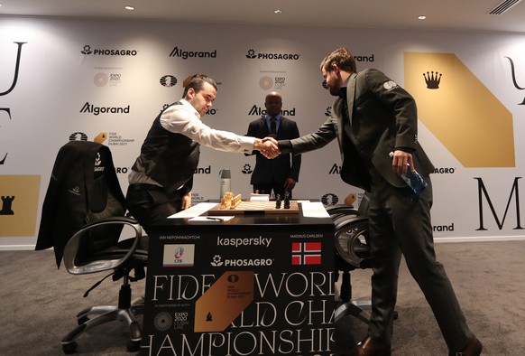 epa09604896 Defending World Champion Magnus Carlsen (R) of Norway shakes hands with challenger Ian Nepomniachtchi of Russia before the staart of the first round of FIDE World Chess Championship during the EXPO 2020 Dubai in Dubai, United Arab Emirates, 26 November 2021. EPA/ALI HAIDER