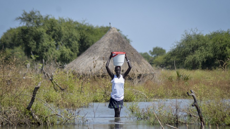 FILE - A woman carries a bucket on her head as she wades through floodwaters in the village of Wang Chot, Old Fangak county, Jonglei state, South Sudan on Nov. 26, 2020. A petition to stop the revival ...