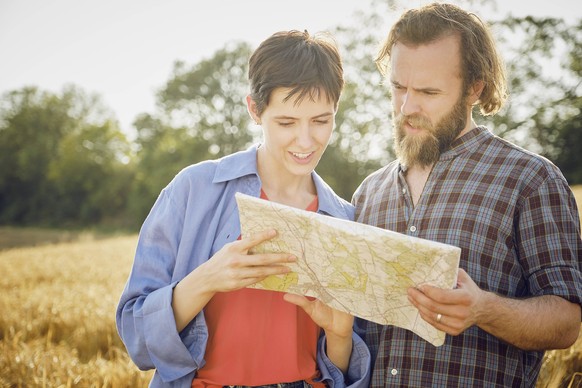 Young woman reading map standing with man in field model released, Symbolfoto property released, PWF01116