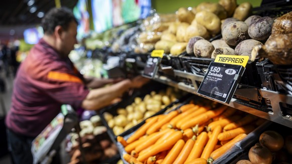 Ein Mitarbeiter raeumt Gemuese ein, neben einem Schild mit der Aufschrift "Tiefpreis" in der Migros Limmatplatz, aufgenommen anlaesslich einer Medienkonferenz zu Neuerungen in den Migros-Sup ...