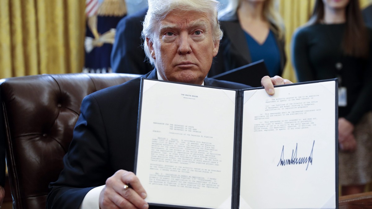 epa05747184 US President Donald Trump displays one of five executive orders he signed related to the oil pipeline industry in the oval office of the White House in Washington, DC, USA, 24 January 2017 ...