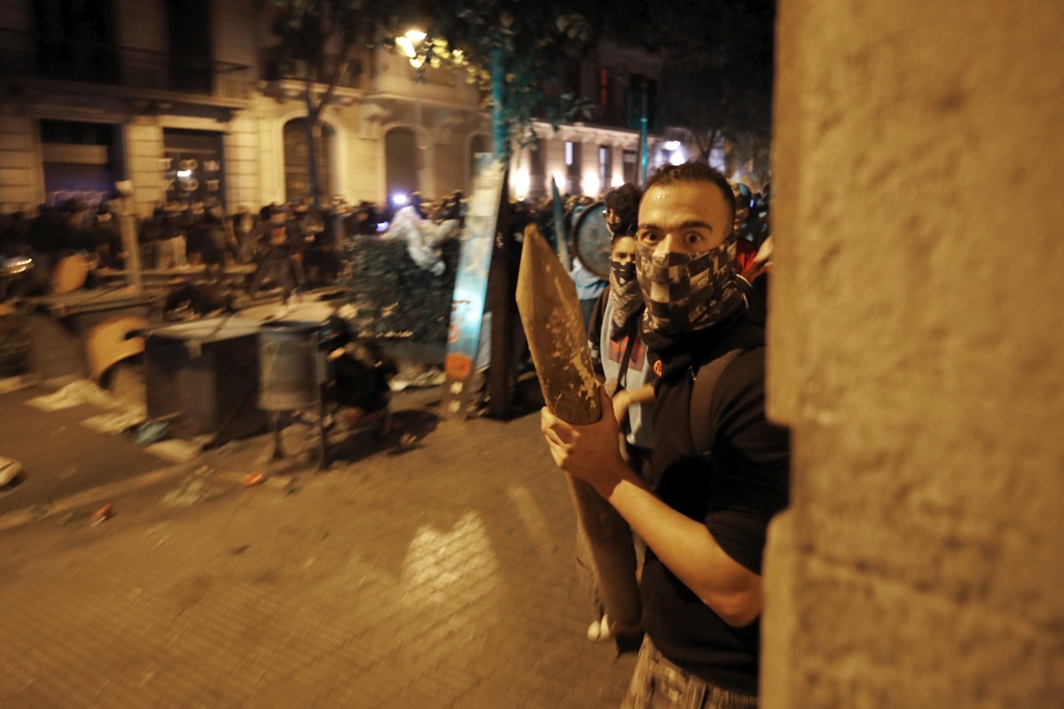 A protestors holding a wooden stake looks from behind a street corner during clashes with police in Barcelona, Spain, Thursday, Oct. 17, 2019. Catalonia's separatist leader vowed Thursday to hold ...