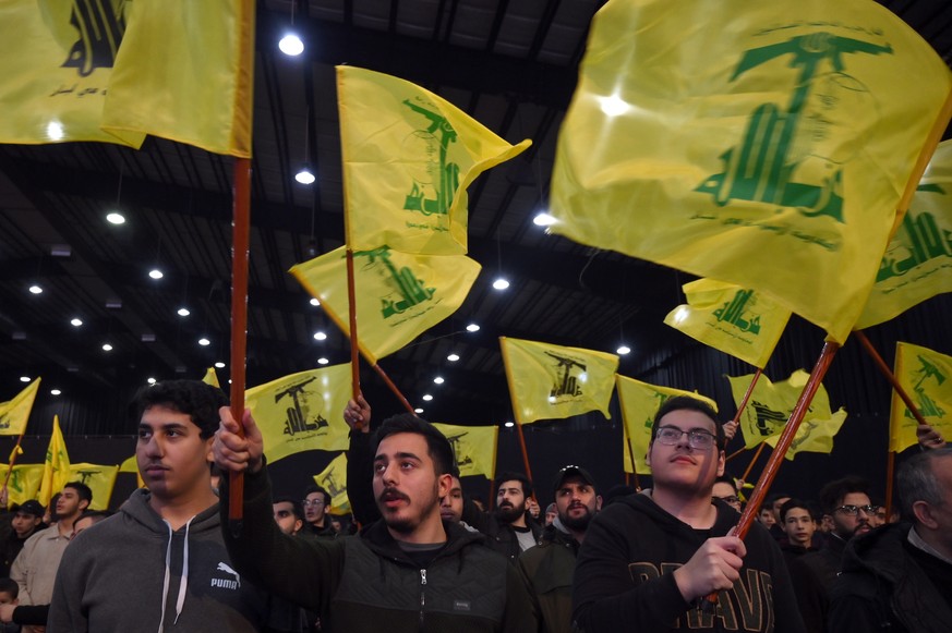 epa10470738 Supporters of Hezbollah wave Hezbollah flags as they listen to a speech of Hezbollah leader Sayyed Hassan Nasrallah delivered on a screen during a rally to mark the Martyrs leaders Day in  ...