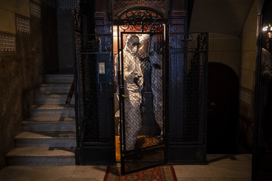 Wearing protective suits to prevent infection, mortuary workers move the body of an elderly person who died of COVID-19 from an elevator after removing it from a nursing home in Barcelona, Spain, Nov. ...