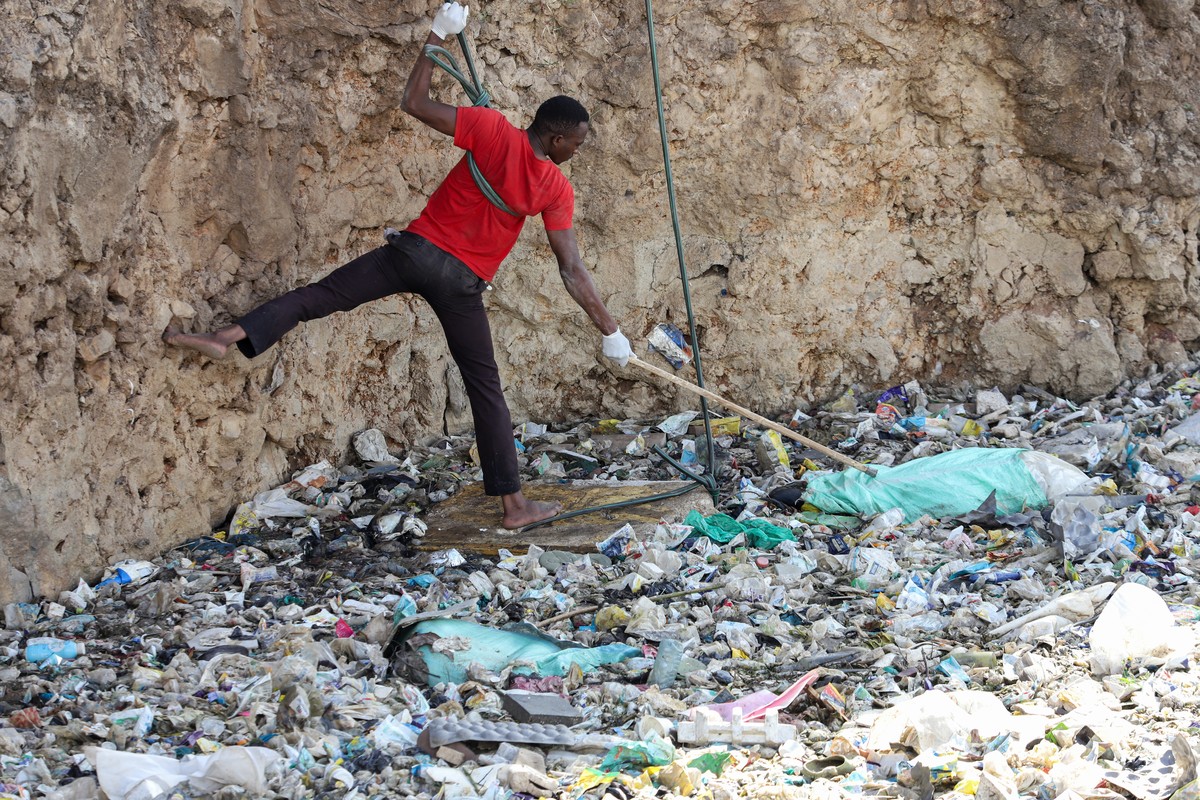 epa11474619 A man reaches a body wrapped in a bag as he tries to retrieve it inside a quarry turned into a dump site at Embakasi area in Nairobi, Kenya, 12 July 2024. Police stated that six severely m ...