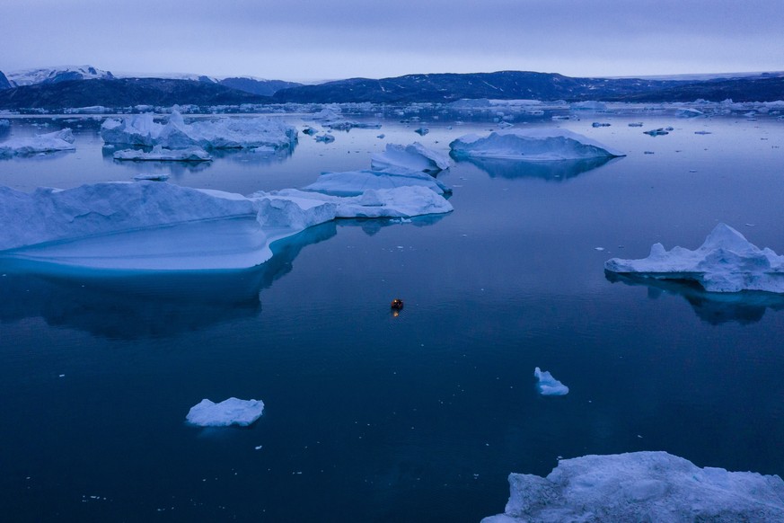 A boat navigates at night between icebergs in eastern Greenland, late Friday, Aug. 15, 2019. Greenland has been melting faster in the last decade and this summer, it has seen two of the biggest melts  ...