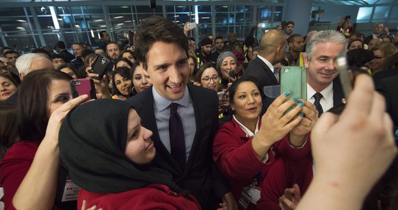 Canadian Prime Minister Justin Trudeau, centre, poses for a selfies with workers before he greets refugees from Syria at Pearson International airport, in Toronto, on Thursday, Dec. 10, 2015. (Nathan  ...