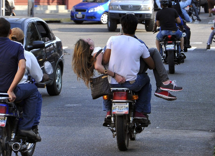 In this Tuesday, Feb. 18, 2014 photo, injured university student Genesis Carmona is carried by a youth on the back of a motorcycle during an anti-government protest in Valencia, Venezuela. Family memb ...