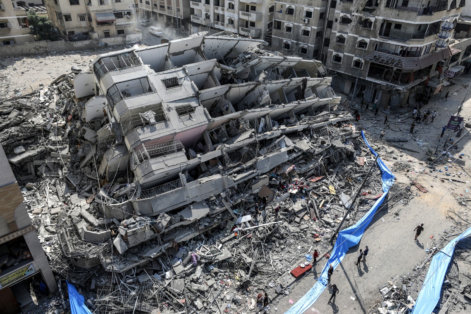 epaselect epa10907217 An aerial view shows people inspecting the destroyed Al-Aklouk Tower following Israeli air strikes, in Gaza City, 08 October 2023. The air strikes, in retaliation for the 07 Octo ...