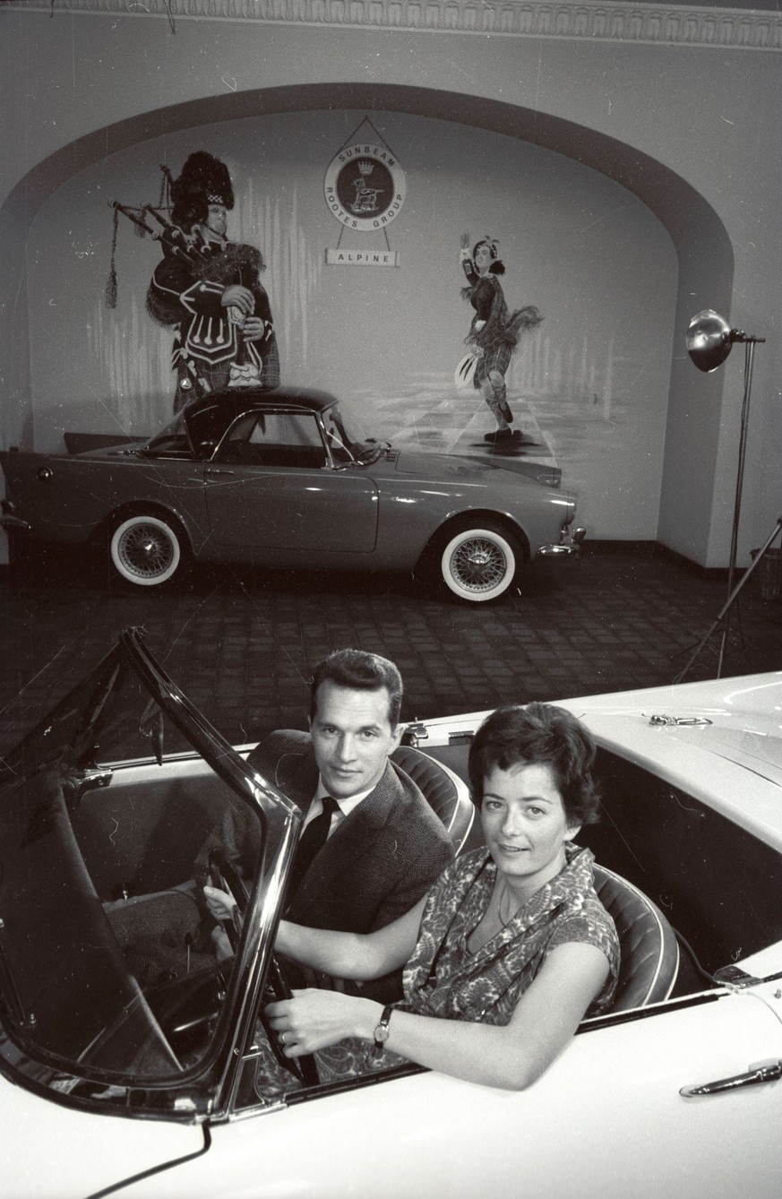 Photographer: Zsolt, Somorjai Title: Geneva, Motor Show, 10.-23.  March 1960 Description: Man and woman in car, in the background: Sunbeam Rootes Group Alpine Dated: 3/1960