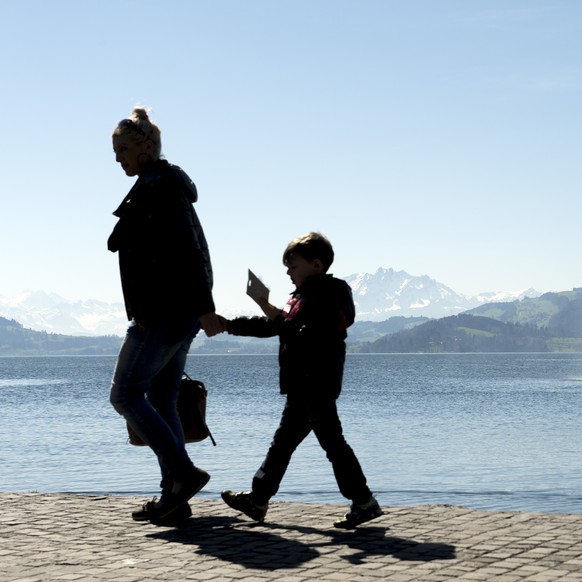 Da muss ich halt zu Fuss gehen, bin ja extra um 4:00 Uhr aufgestanden. Zwei Menschen spazieren in der Naehe eines Wasserstrahls am Ufer des Zugersee, in Zug, am Mittwoch, 8 April 2015. (KEYSTONE/Anthony Anex)