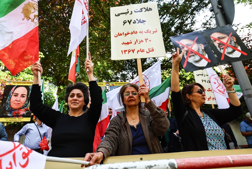 epa11355187 Protesters of the National Council of Resistance of Iran (NWRI) carry placards with slogans against the late Iranian President Ebrahim Raisi, as they demonstrate against the Iranian regime ...