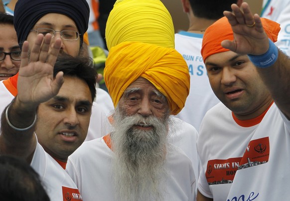 FILE - Centenarian marathon runner Fauja Singh, center, smiles after finishing a 10-kilometer race, held as part of the annual Hong Kong Marathon, in Hong Kong, Feb. 24, 2013. (AP Photo/Vincent Yu, fi ...