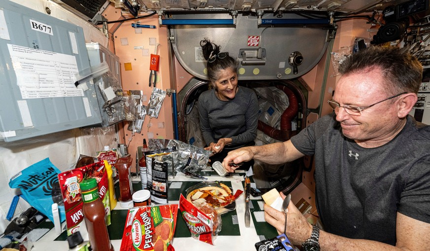 FILE - In this photo provided by NASA, astronauts Suni Williams and Butch Wilmore, both Expedition 71 flight engineers, make pizza aboard the International Space Station's galley located inside t ...