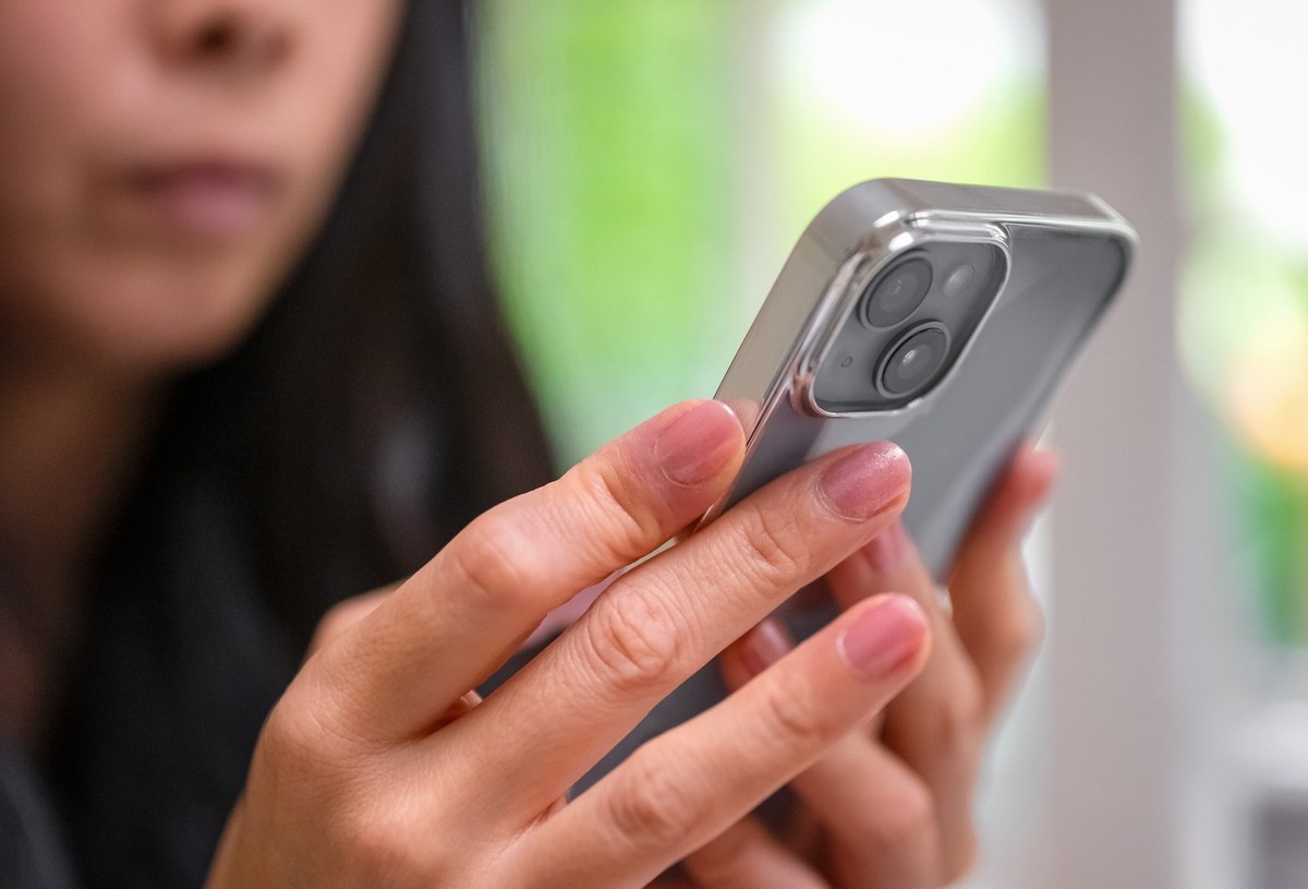 Junge Frau nutzt iPhone (Symbolbild Mobilfunk).