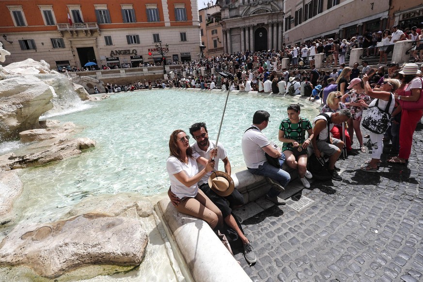 epa06887918 Tourists are seen next to the world-famous Trevi Fountain during a hot and muggy day in Rome, Italy, 14 July 2018. The Italian Health Ministry issued on 13 July, a heat alert for eight Ita ...