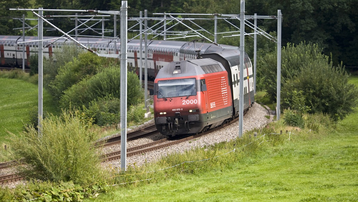 An InterCity train with IC2000 double-storeyed coaches and a Re 460 locomotive of Swiss Federal Railways SBB drives through a curve in the vicinity of Flawil in the canton of St. Gallen, Switzerland, ...