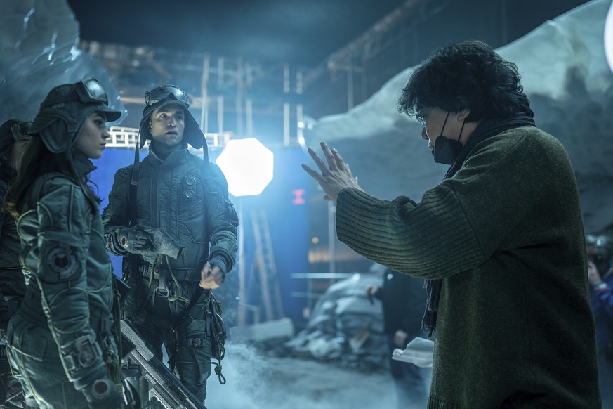 This image released by Warner Bros. Pictures shows actors Anamaria Vartolomei, left, and Robert Pattinson, center, with filmmaker Bong Joon Ho on the set of &quot;Mickey 17.&quot; (Jonathan Olley/Warn ...